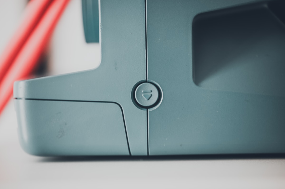 Boîtier gris métallique avec bouton circulaire.