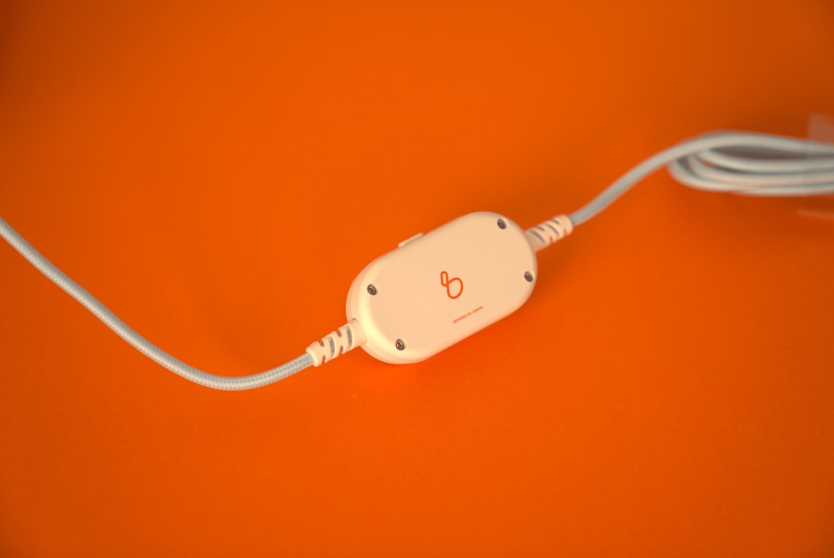 Câble électrique blanc avec connecteur sur fond orange.