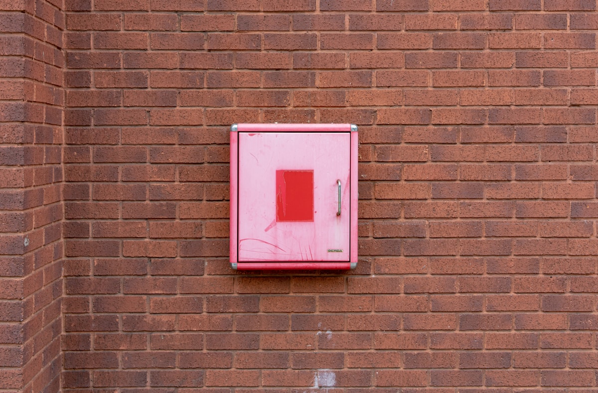 Boîte rouge sur un mur de briques.
