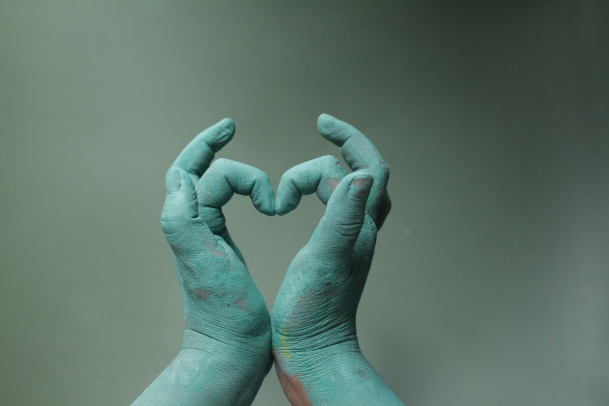 Mains peintes en vert formant un cœur.
