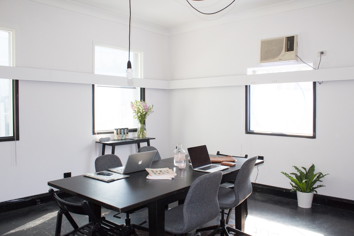 Bureau de travail moderne avec ordinateurs portables et plante verte.