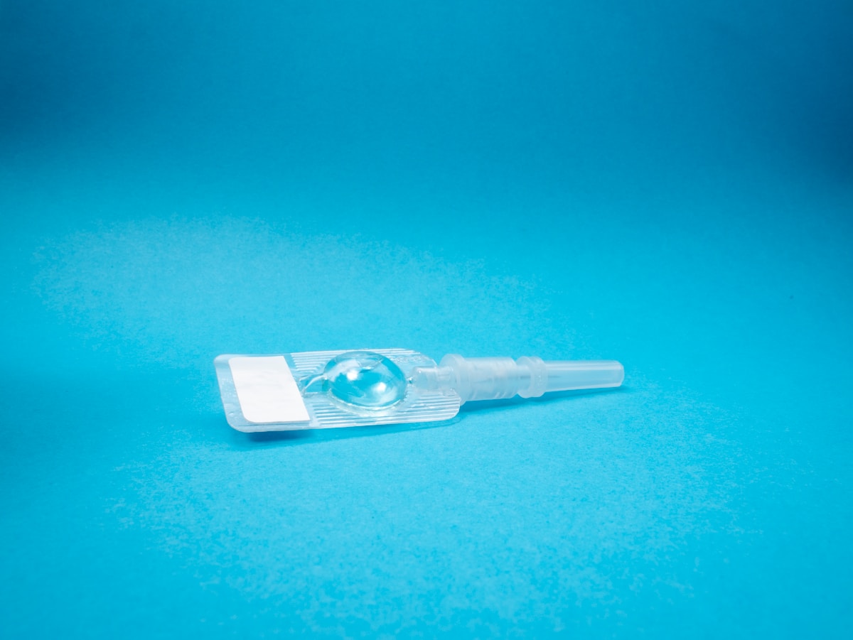 Pipette médicale transparente avec une goutte d'eau sur fond bleu.