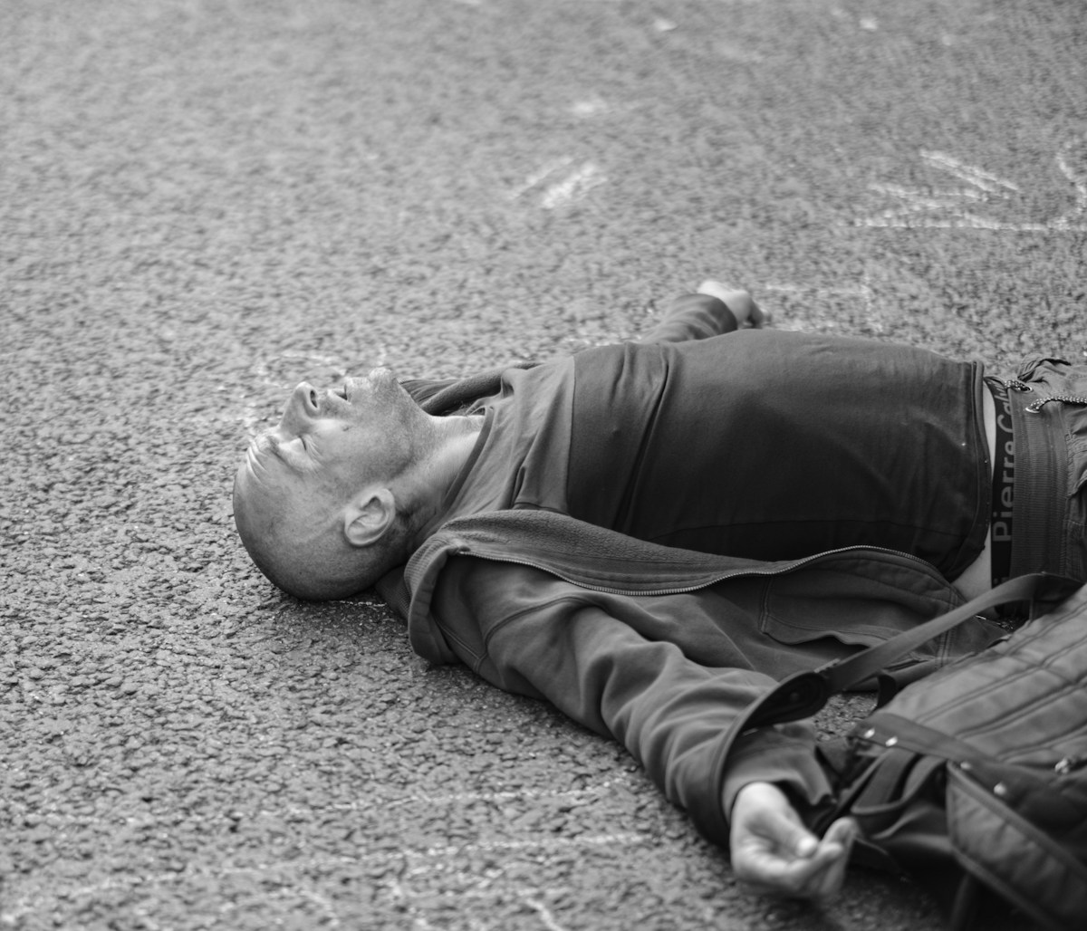 Un homme en veste noire allongé au sol.