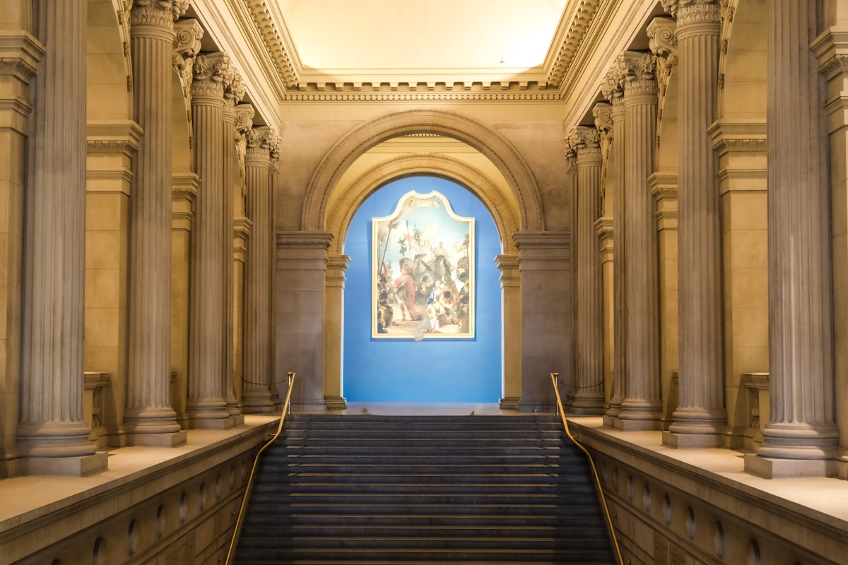 Escalier monumental menant à une peinture murale dans un palais majestueux.