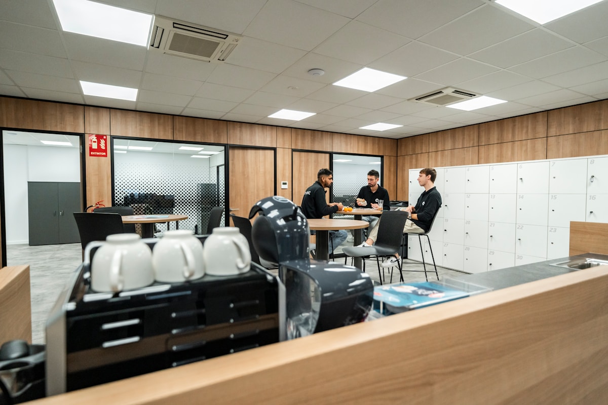 Salle de réunion moderne avec des employés discutant autour d'une table.