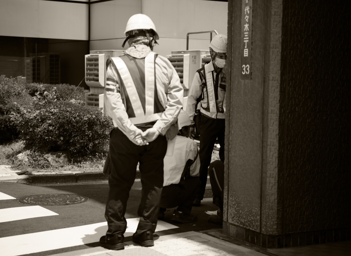 Deux travailleurs en uniforme de sécurité dans un environnement industriel.