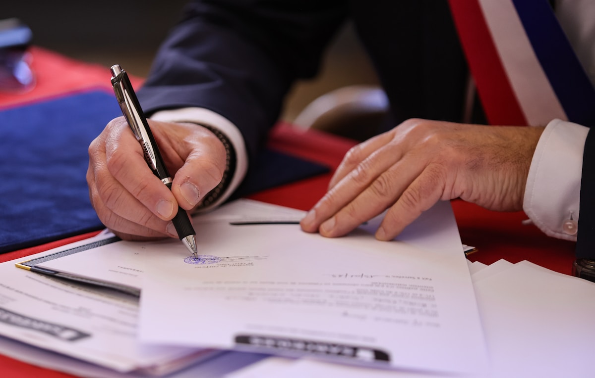 Mains signant un document officiel avec un stylo.