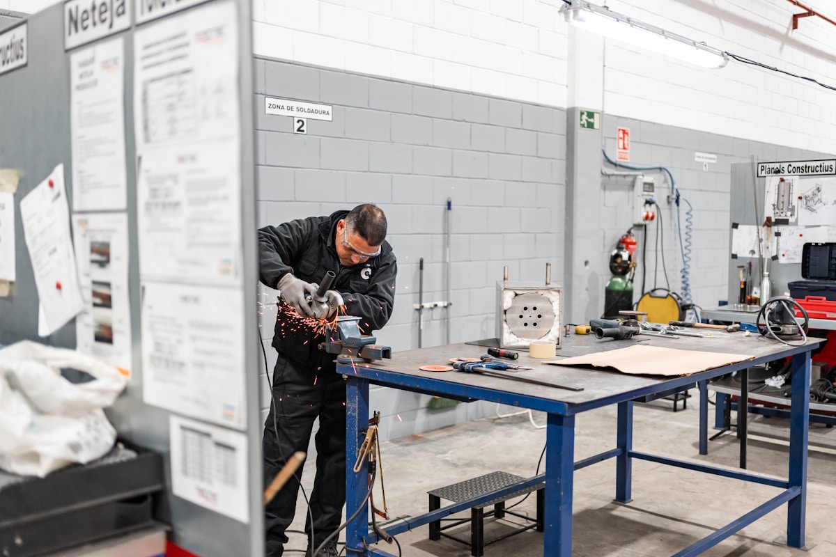 Ouvrier travaillant sur un établi dans un atelier industriel.
