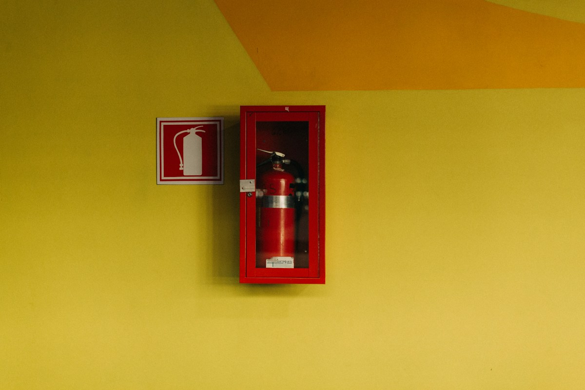 Extincteur rouge dans un coffret mural avec pictogramme.